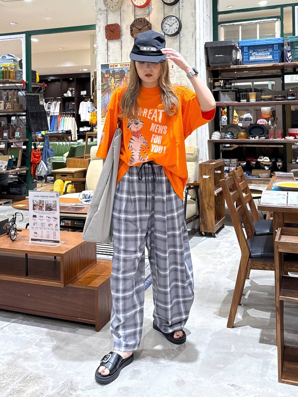 ブラック系のサンダル、グレー系のエコバッグ/サブバッグ、オレンジ系のTシャツ/カットソーを着用したレディースの春コーディネートの2枚目の写真