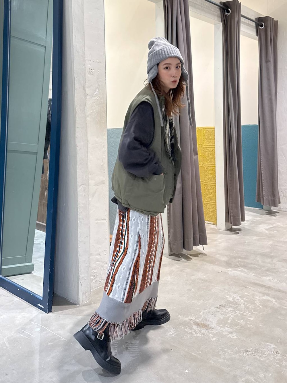 グリーン系のベスト、ブラック系のブーツを着用したレディースの秋コーディネートの2枚目の写真