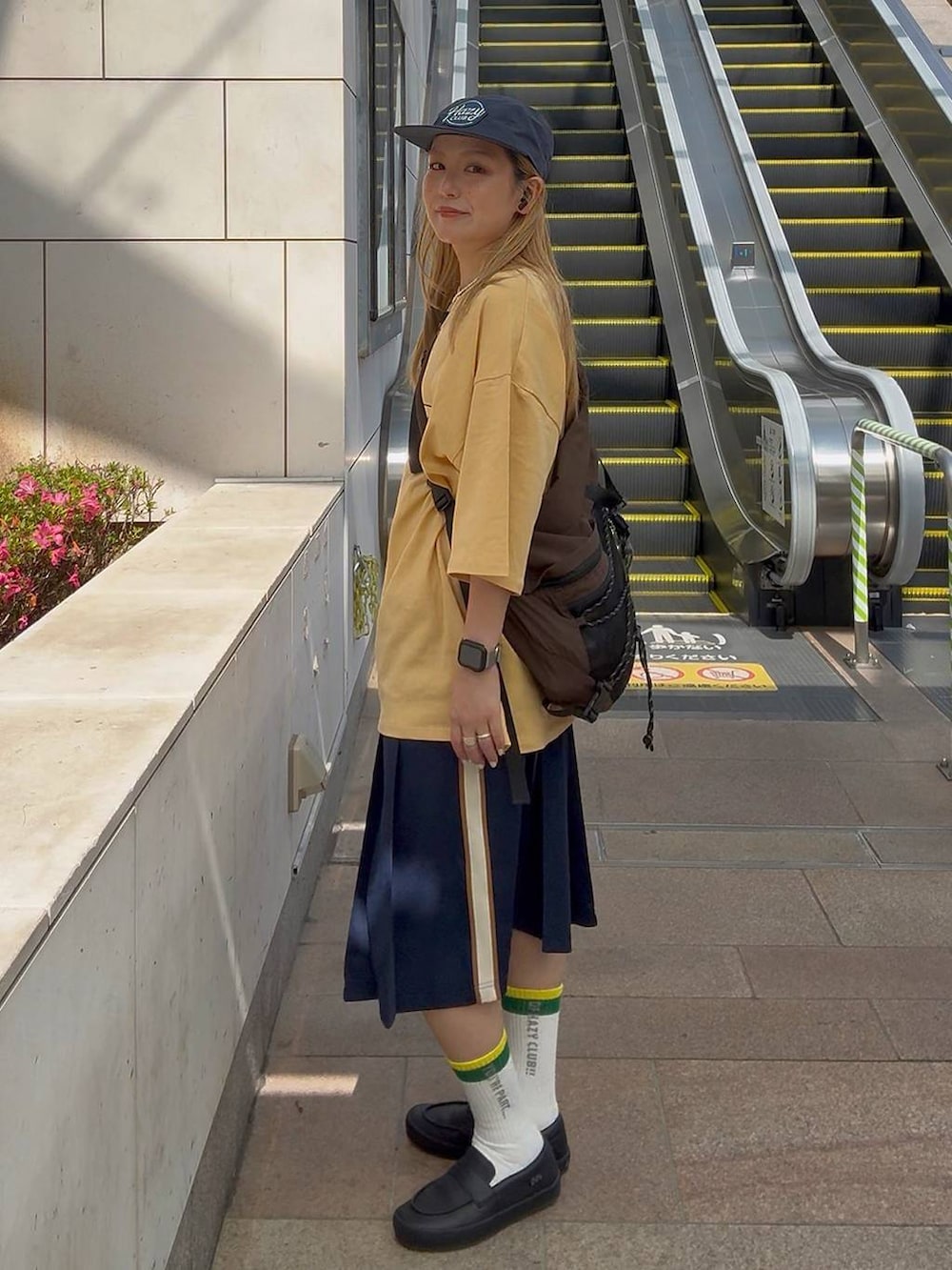 オレンジ系のTシャツ/カットソーを着用したレディースの夏コーディネートの2枚目の写真