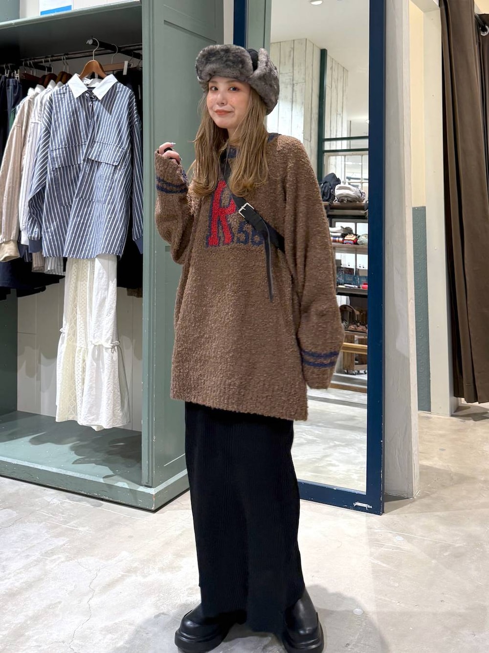 ブラック系のショルダーバッグ、ブラック系のスカート、ブラック系のブーツを着用したレディースの秋コーディネートの2枚目の写真