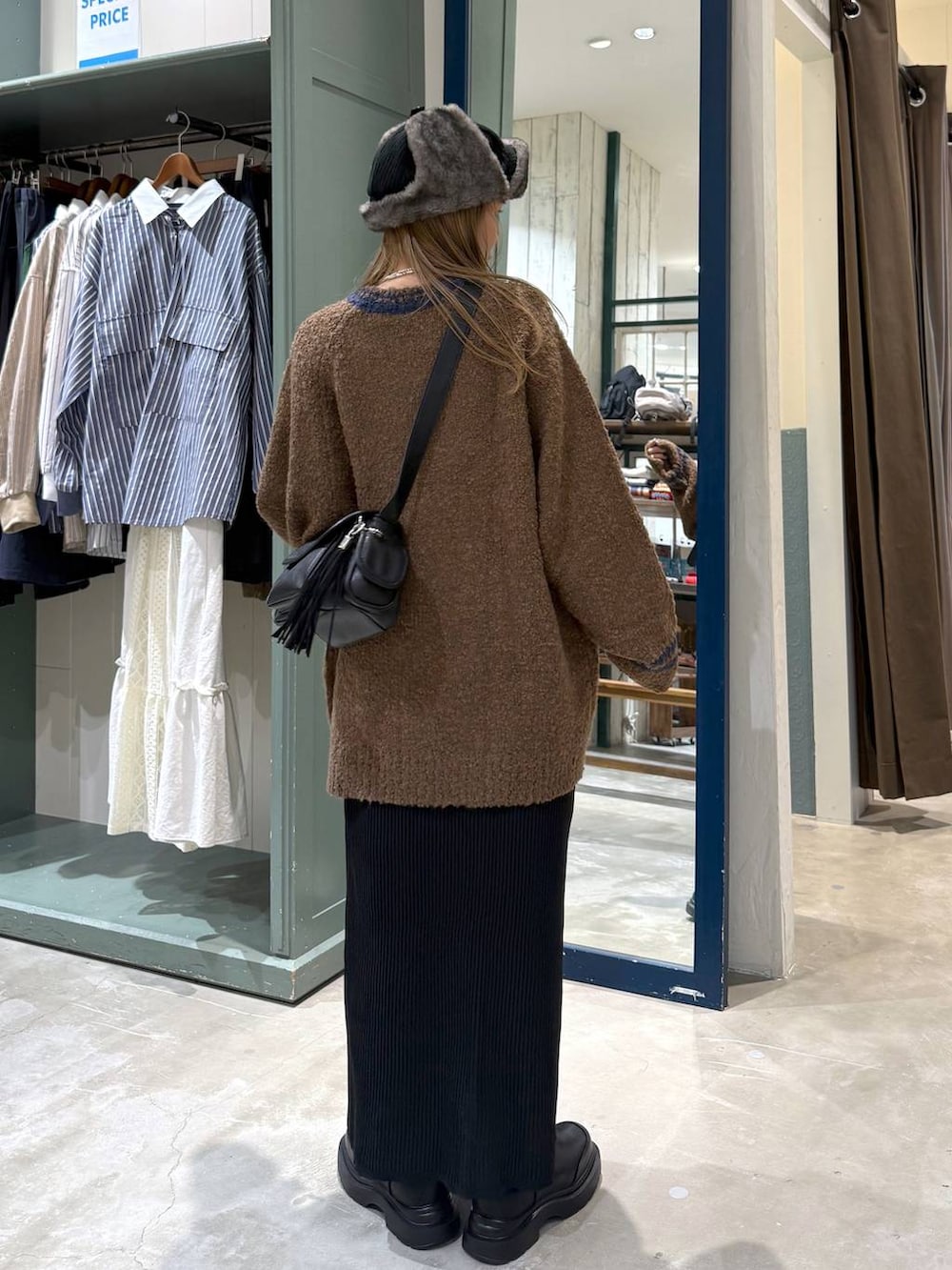 ブラック系のショルダーバッグ、ブラック系のスカート、ブラック系のブーツを着用したレディースの秋コーディネートの4枚目の写真