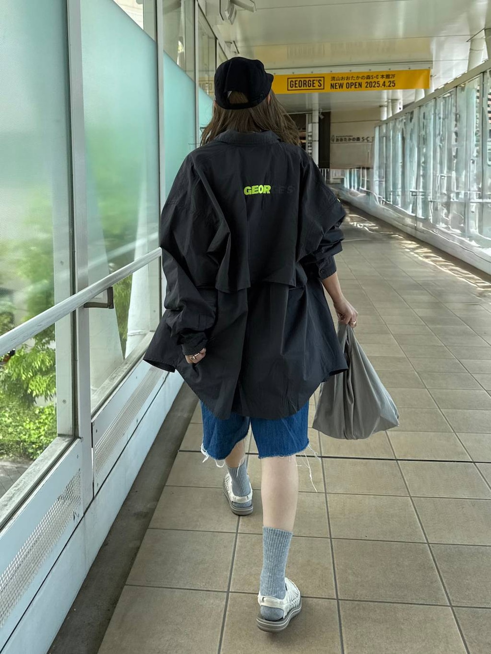 ブルー系のデニムパンツ、グレー系のエコバッグ/サブバッグ、ブラック系のキャップを着用したレディースの春コーディネートの2枚目の写真