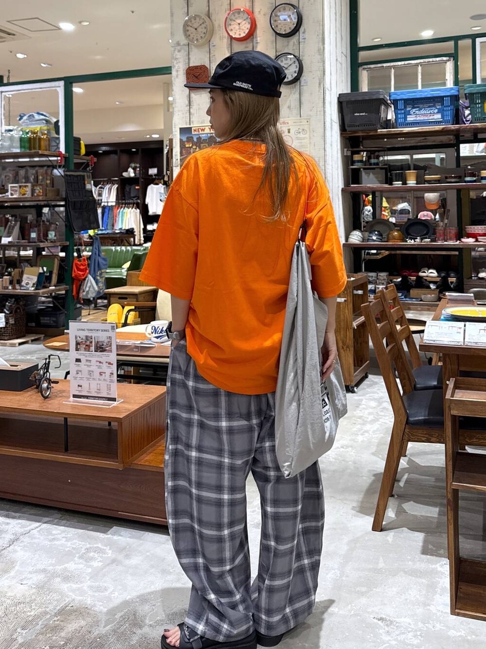 ブラック系のサンダル、グレー系のエコバッグ/サブバッグ、オレンジ系のTシャツ/カットソーを着用したレディースの春コーディネートの4枚目の写真