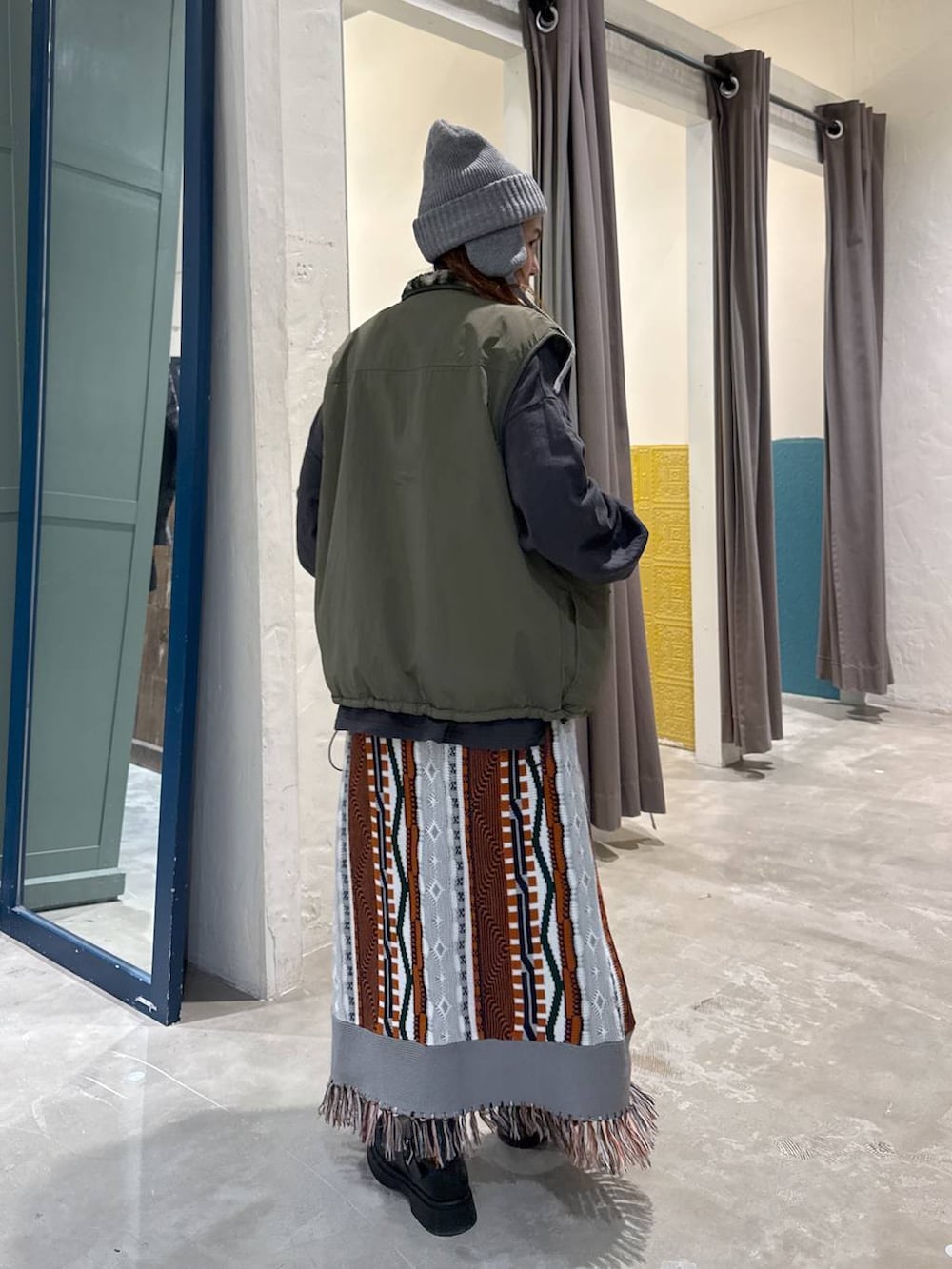 グリーン系のベスト、ブラック系のブーツを着用したレディースの秋コーディネートの5枚目の写真