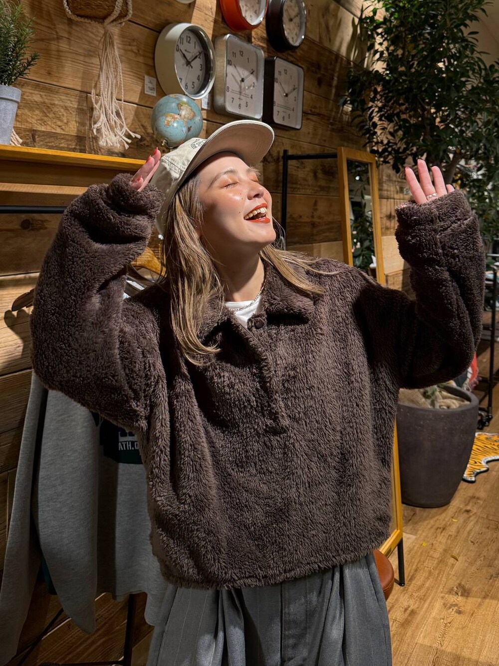 ブラウン系のポロシャツ、ホワイト系のキャップを着用したレディースの冬コーディネートの2枚目の写真