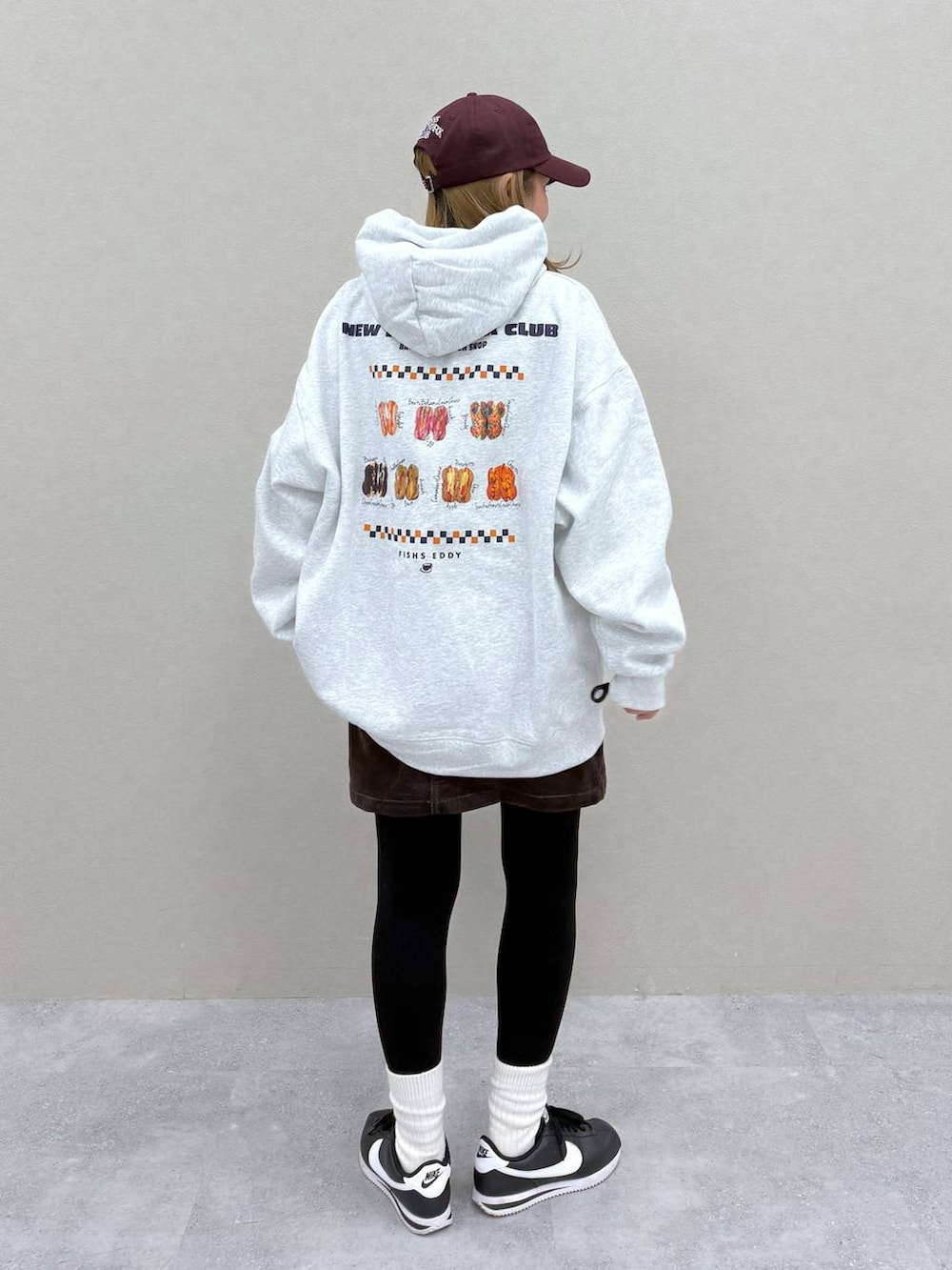 ブラウン系のスカート、グレー系のパーカー、レッド系のキャップを着用したレディースの秋コーディネートの4枚目の写真