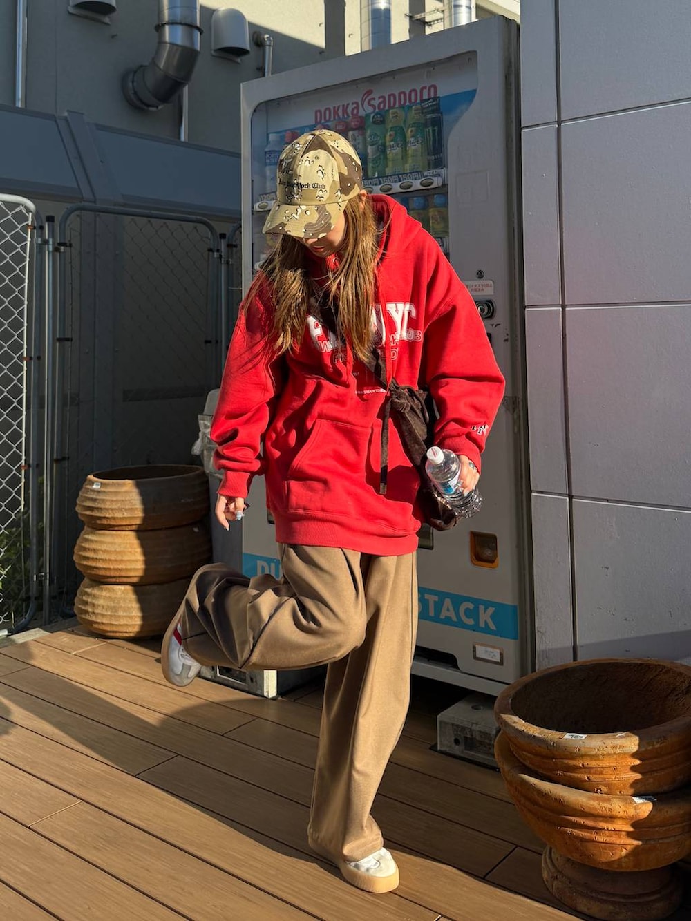 レッド系のパーカー、ベージュ系のキャップを着用したレディースの秋コーディネートの3枚目の写真