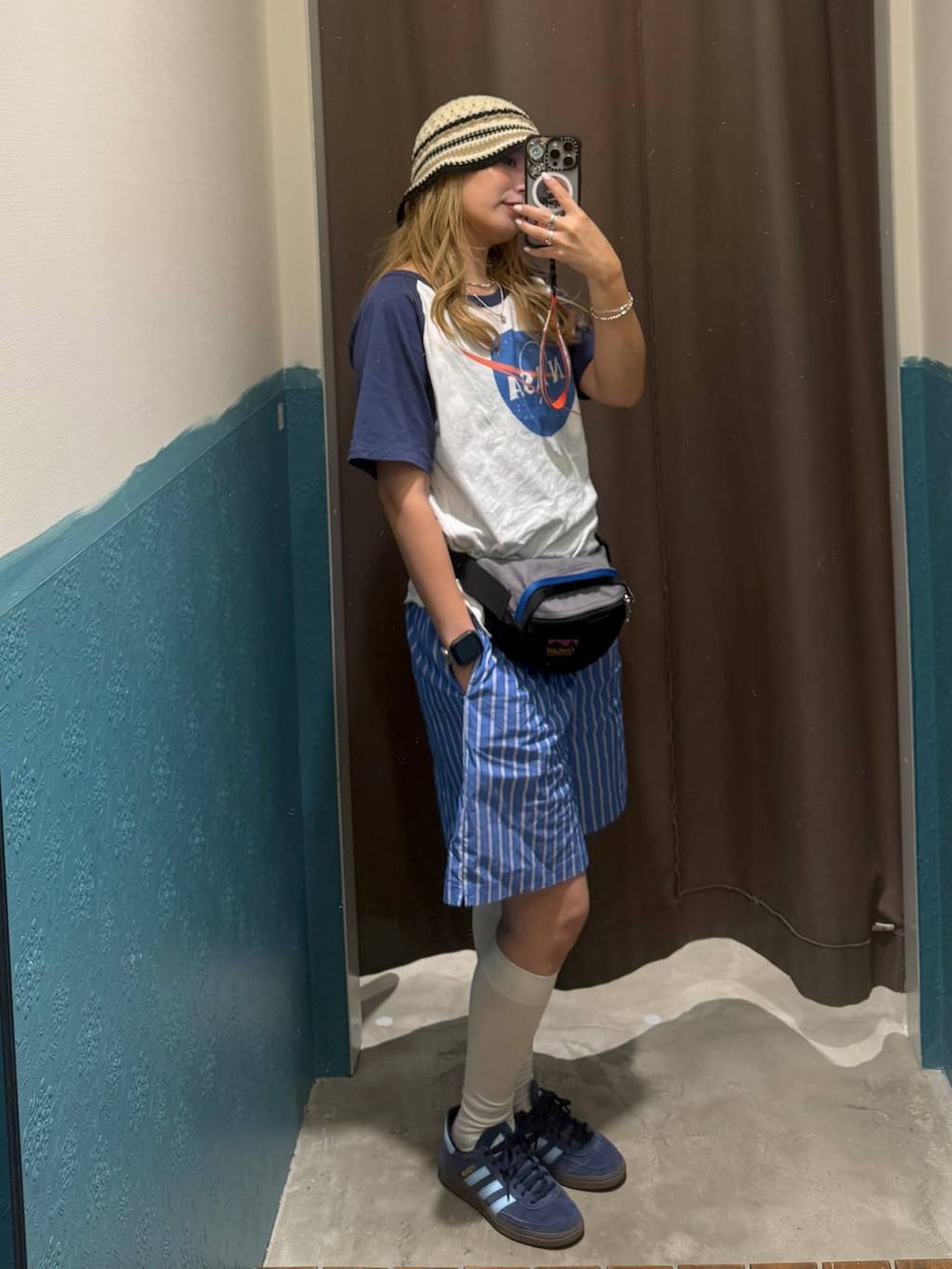 グレー系のボディバッグ/ウエストポーチ、ブルー系のTシャツ/カットソー、ベージュ系のハットを着用したレディースの夏コーディネートの2枚目の写真