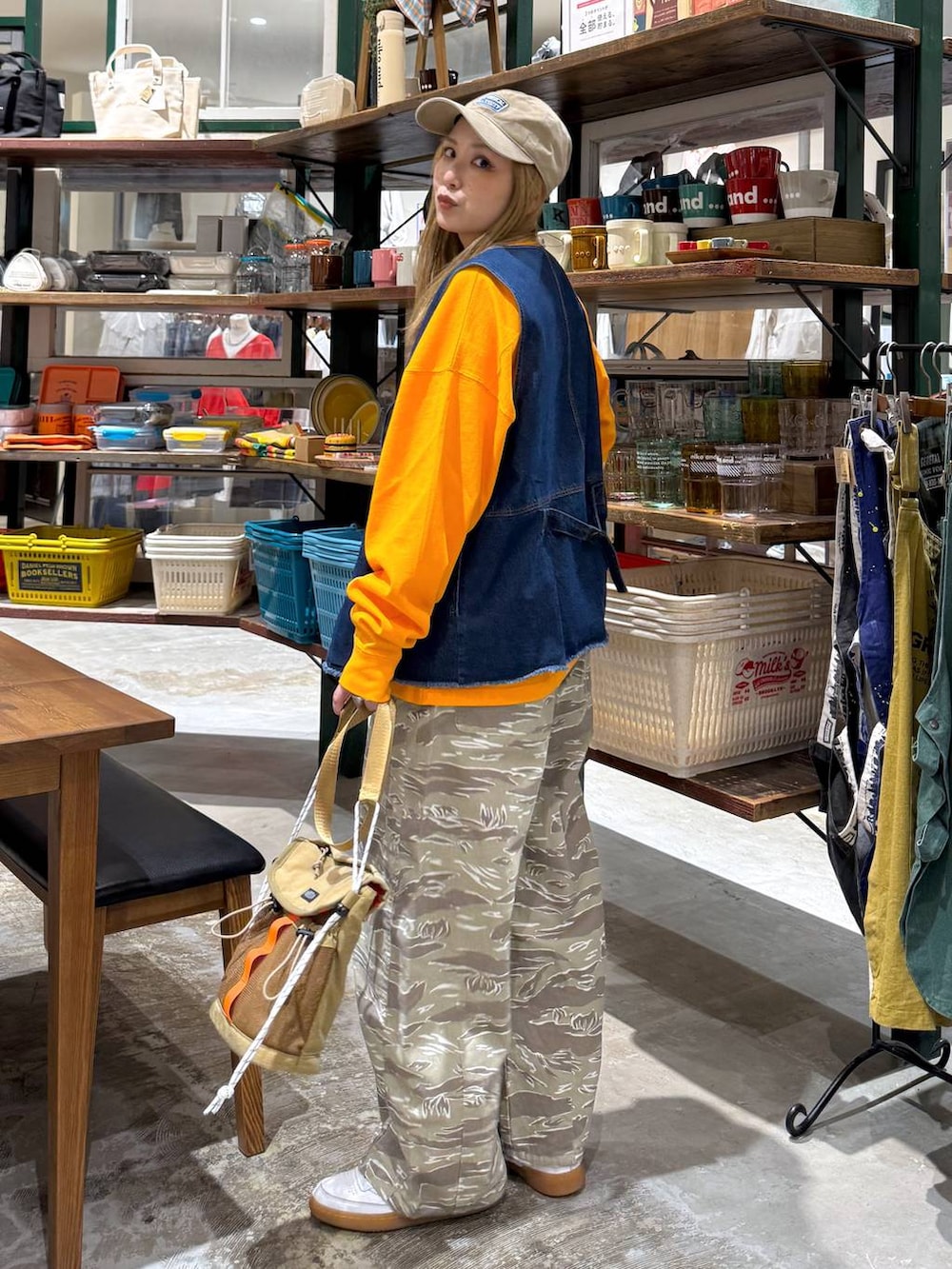 ブルー系のベスト、ベージュ系のキャップを着用したレディースの春コーディネートの3枚目の写真