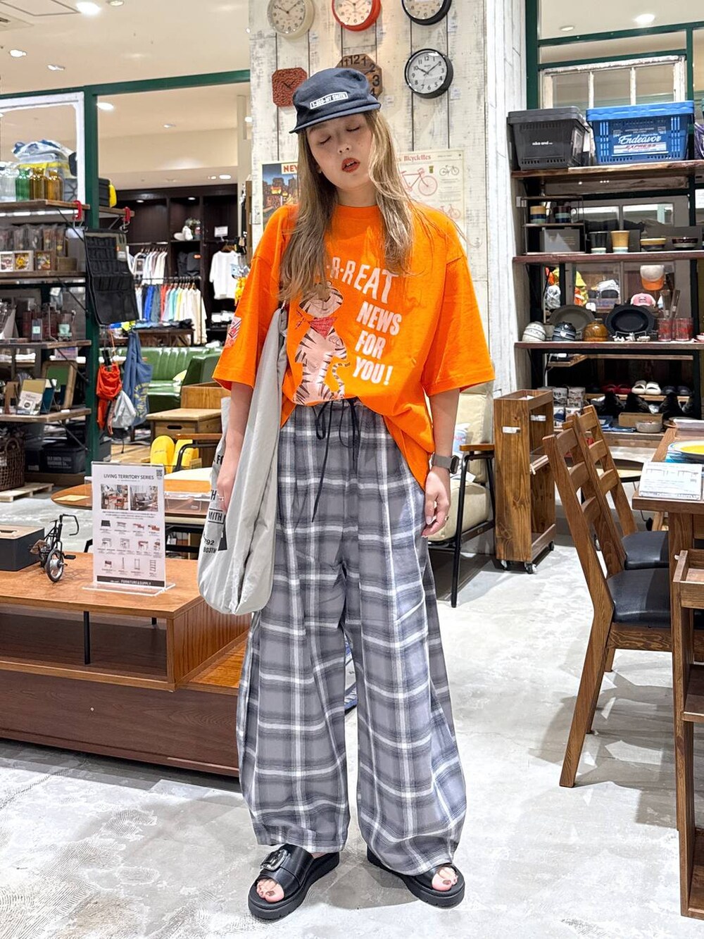 ブラック系のサンダル、グレー系のエコバッグ/サブバッグ、オレンジ系のTシャツ/カットソーを着用したレディースの春コーディネートの3枚目の写真