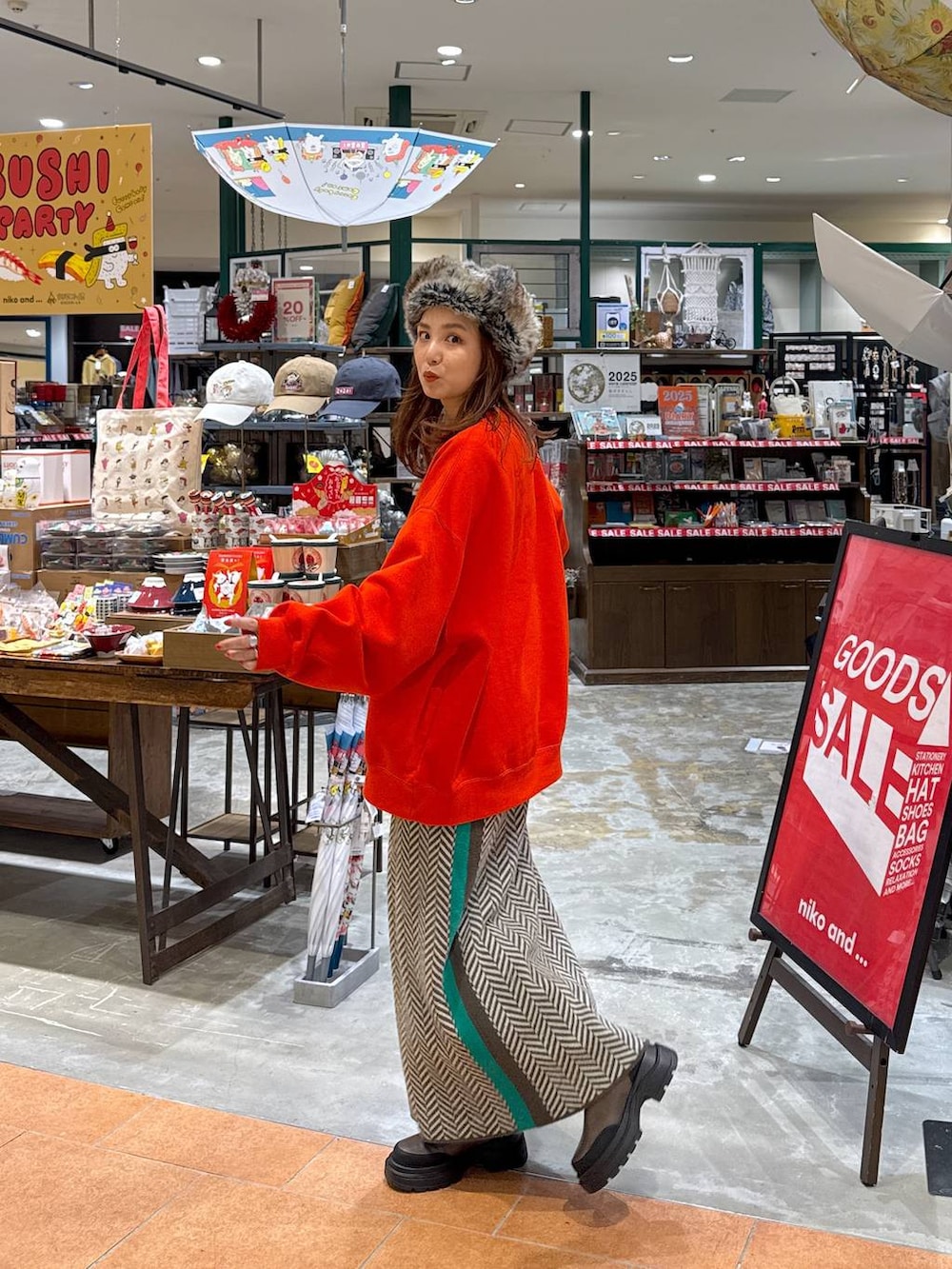 オレンジ系のスウェット、ブラウン系のブーツ、ブラウン系のスカートを着用したレディースの冬コーディネートの2枚目の写真