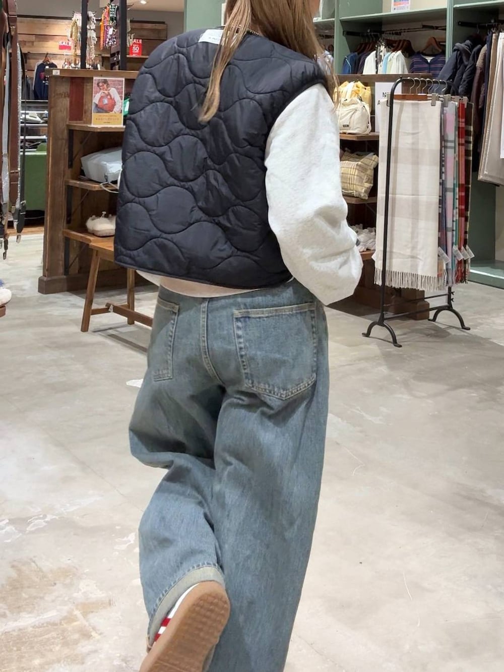 ブラック系のベスト、ベージュ系のスウェット、ブルー系のデニムパンツを着用したレディースの冬コーディネートの3枚目の写真