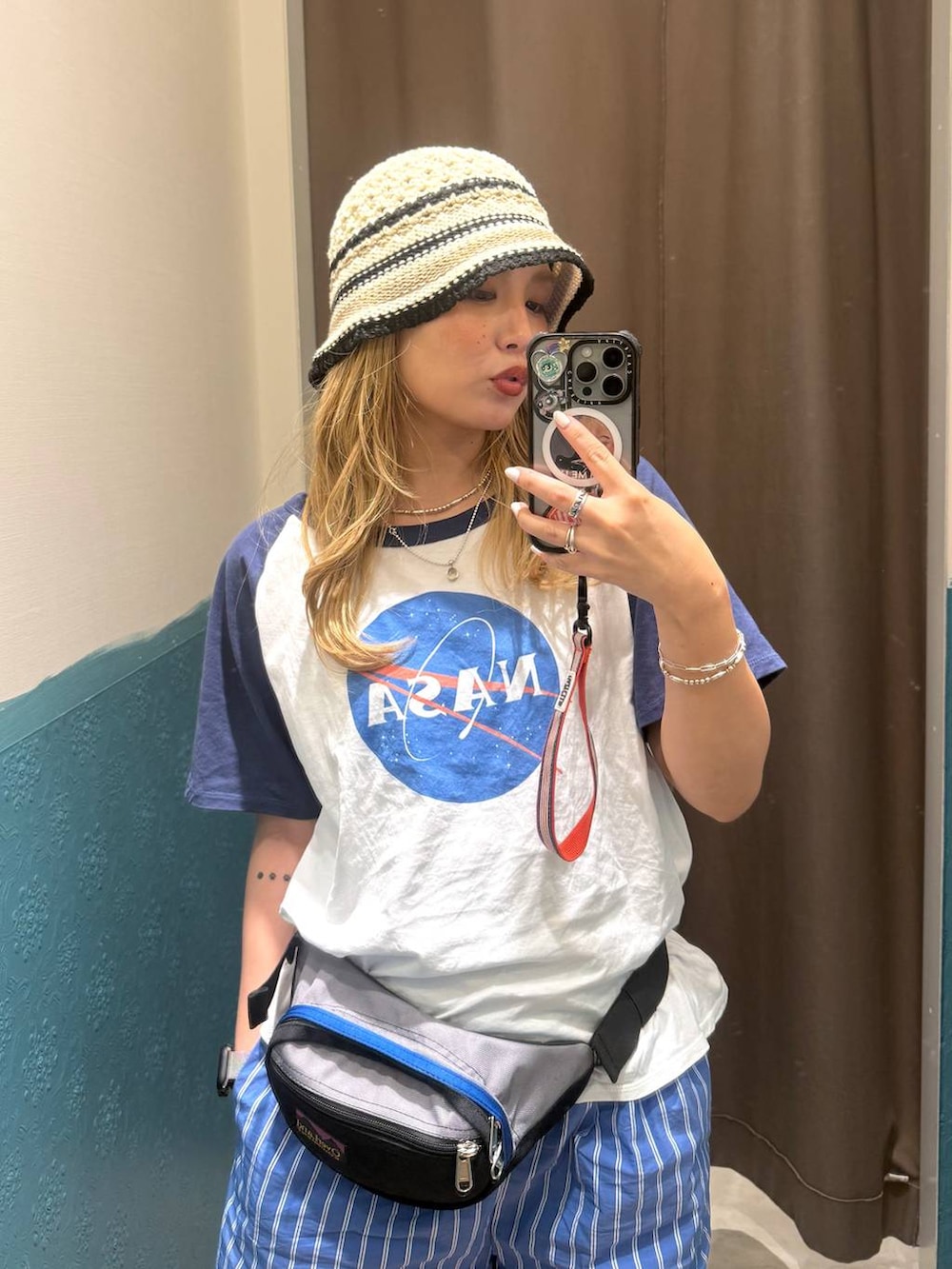 グレー系のボディバッグ/ウエストポーチ、ブルー系のTシャツ/カットソー、ベージュ系のハットを着用したレディースの夏コーディネートの4枚目の写真