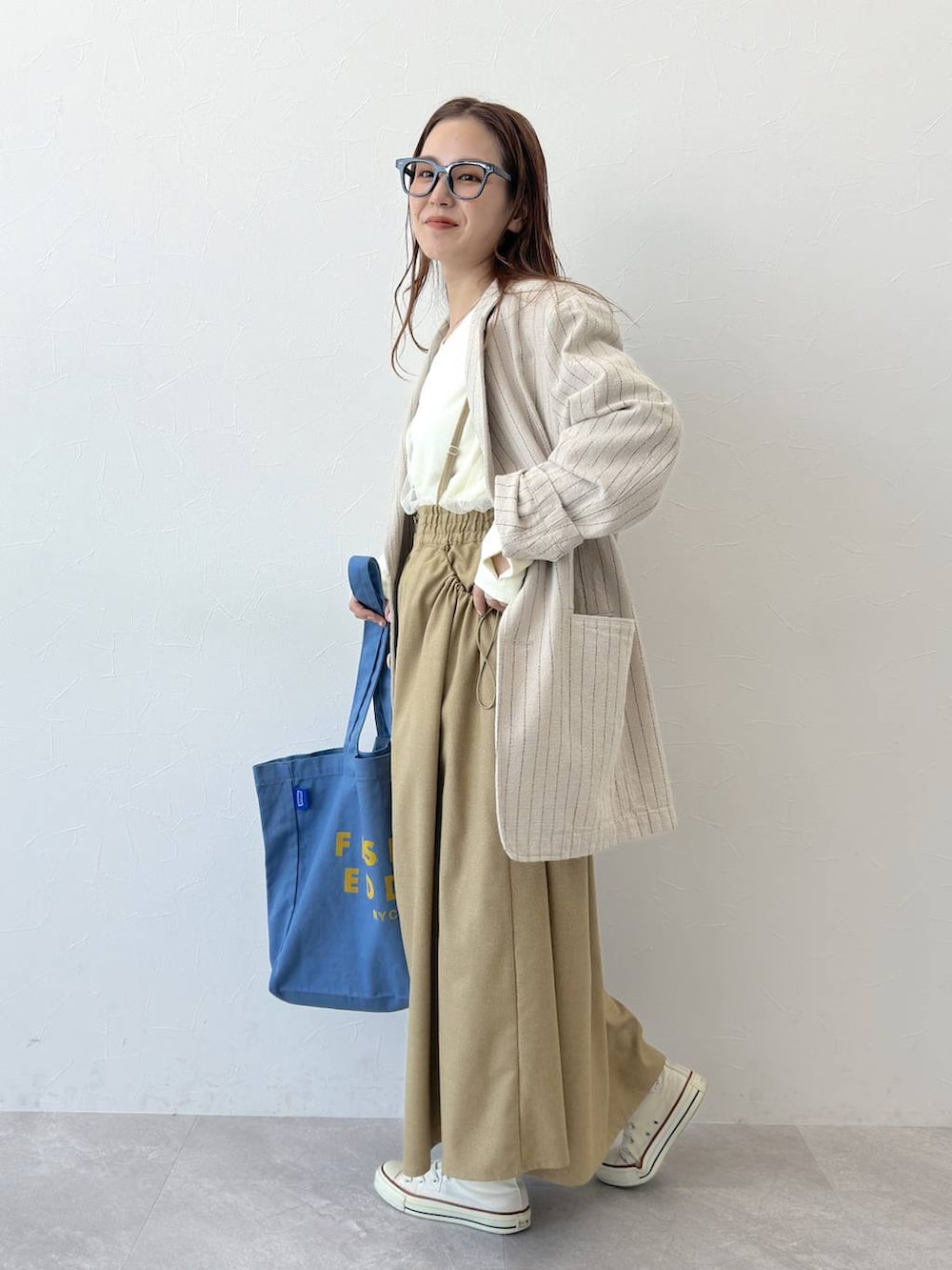 ベージュ系のテーラードジャケット、ブルー系のトートバッグ、ホワイト系のスウェットを着用したレディースの冬コーディネートの2枚目の写真