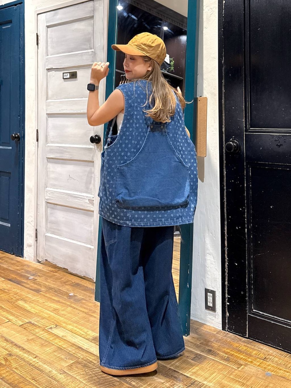 ホワイト系のタンクトップ、イエロー系のキャップを着用したレディースの夏コーディネートの3枚目の写真