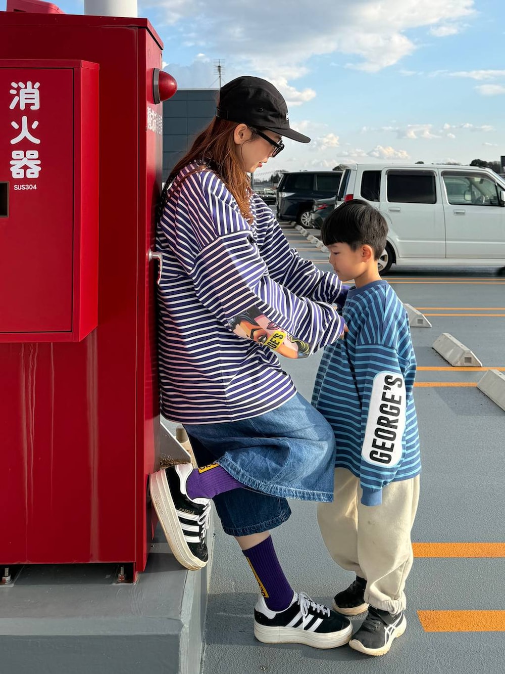 ベージュ系のショルダーバッグ、ブルー系のデニムパンツ、ブラック系のキャップを着用したレディースの春コーディネートの2枚目の写真