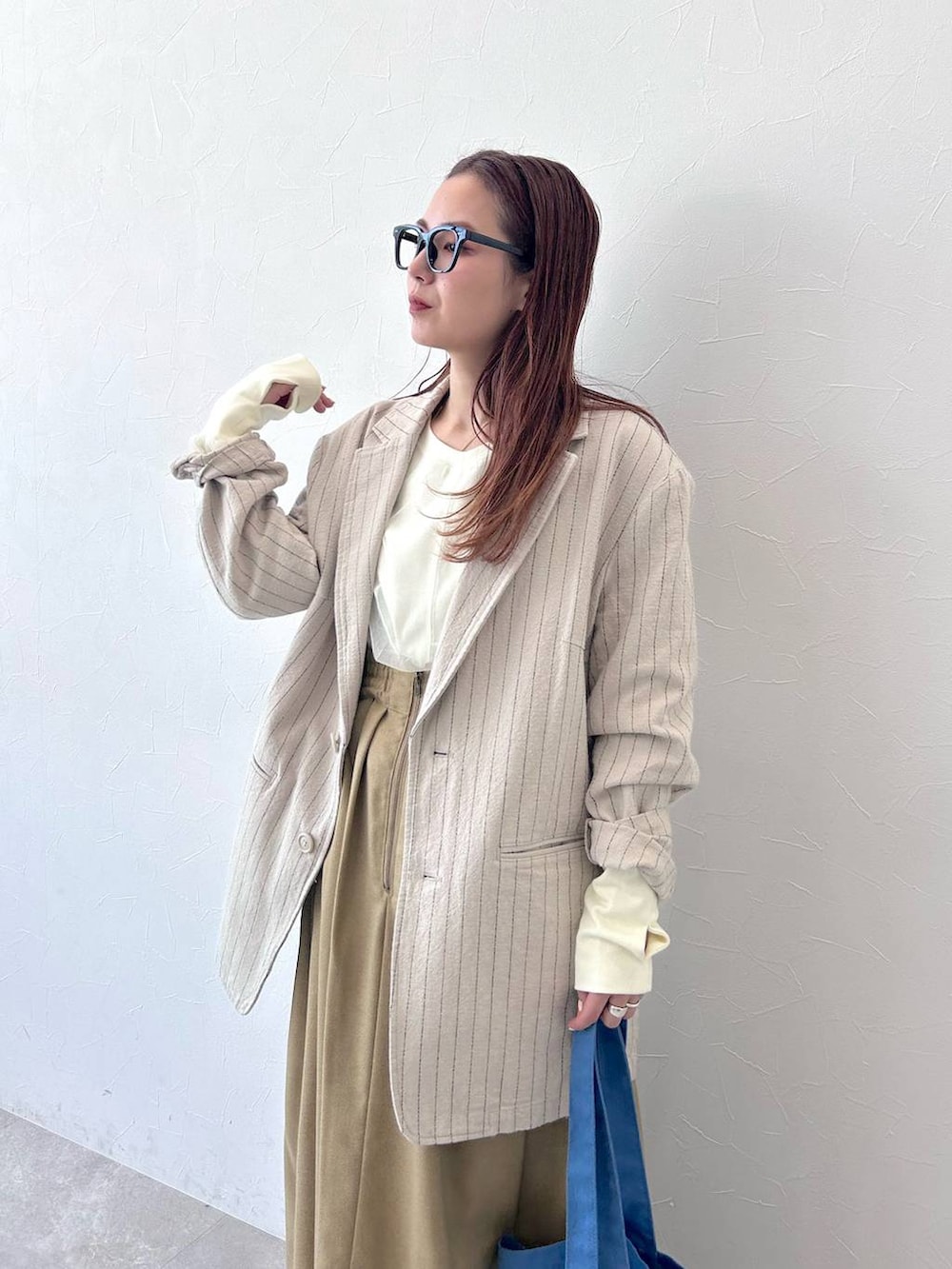 ベージュ系のテーラードジャケット、ブルー系のトートバッグ、ホワイト系のスウェットを着用したレディースの冬コーディネートの4枚目の写真