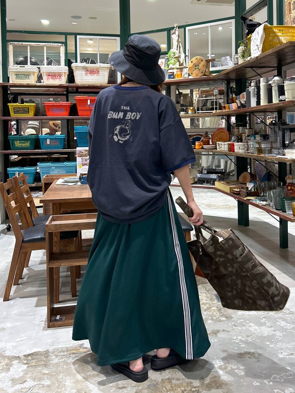 ブラック系のサンダル、ブラウン系のトートバッグ、グリーン系のスカートを着用したレディースの夏コーディネートの3枚目の写真