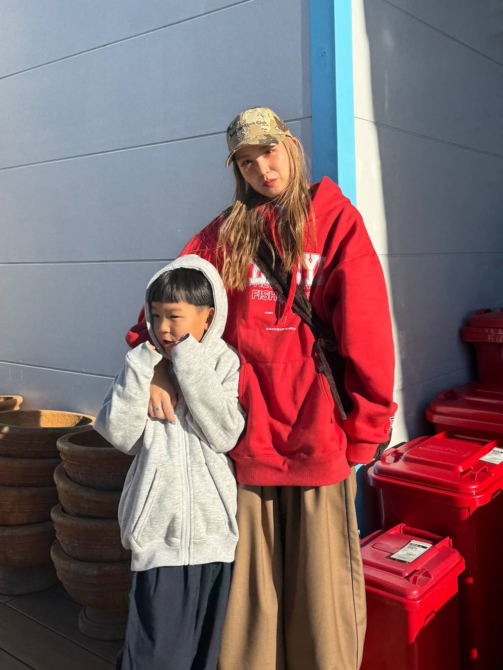 レッド系のパーカー、ベージュ系のキャップを着用したレディースの秋コーディネートの4枚目の写真