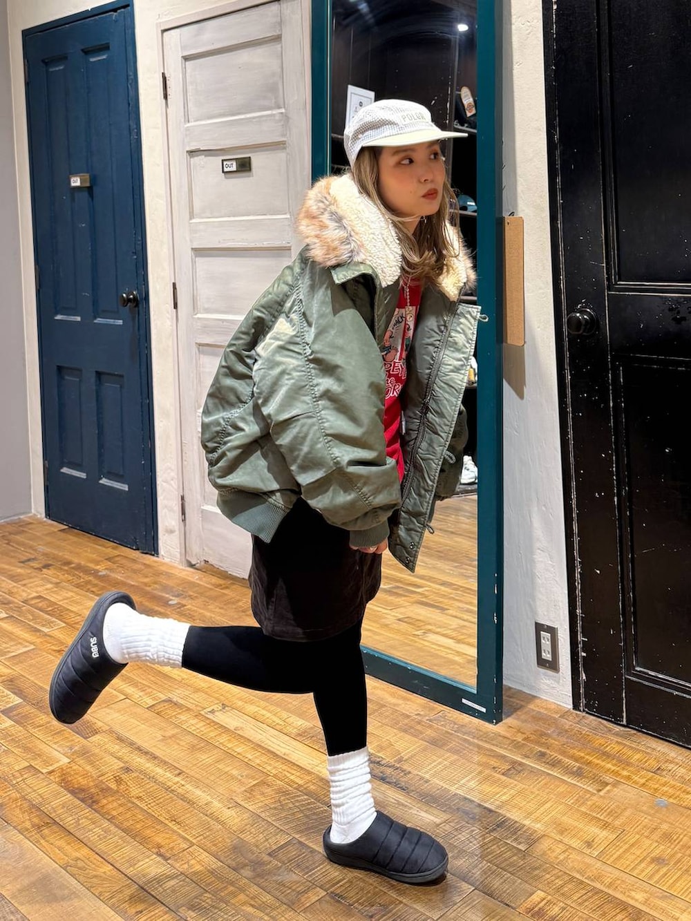 ブラウン系のスカート、グリーン系のブルゾン、レッド系のスウェットを着用したレディースの冬コーディネートの2枚目の写真