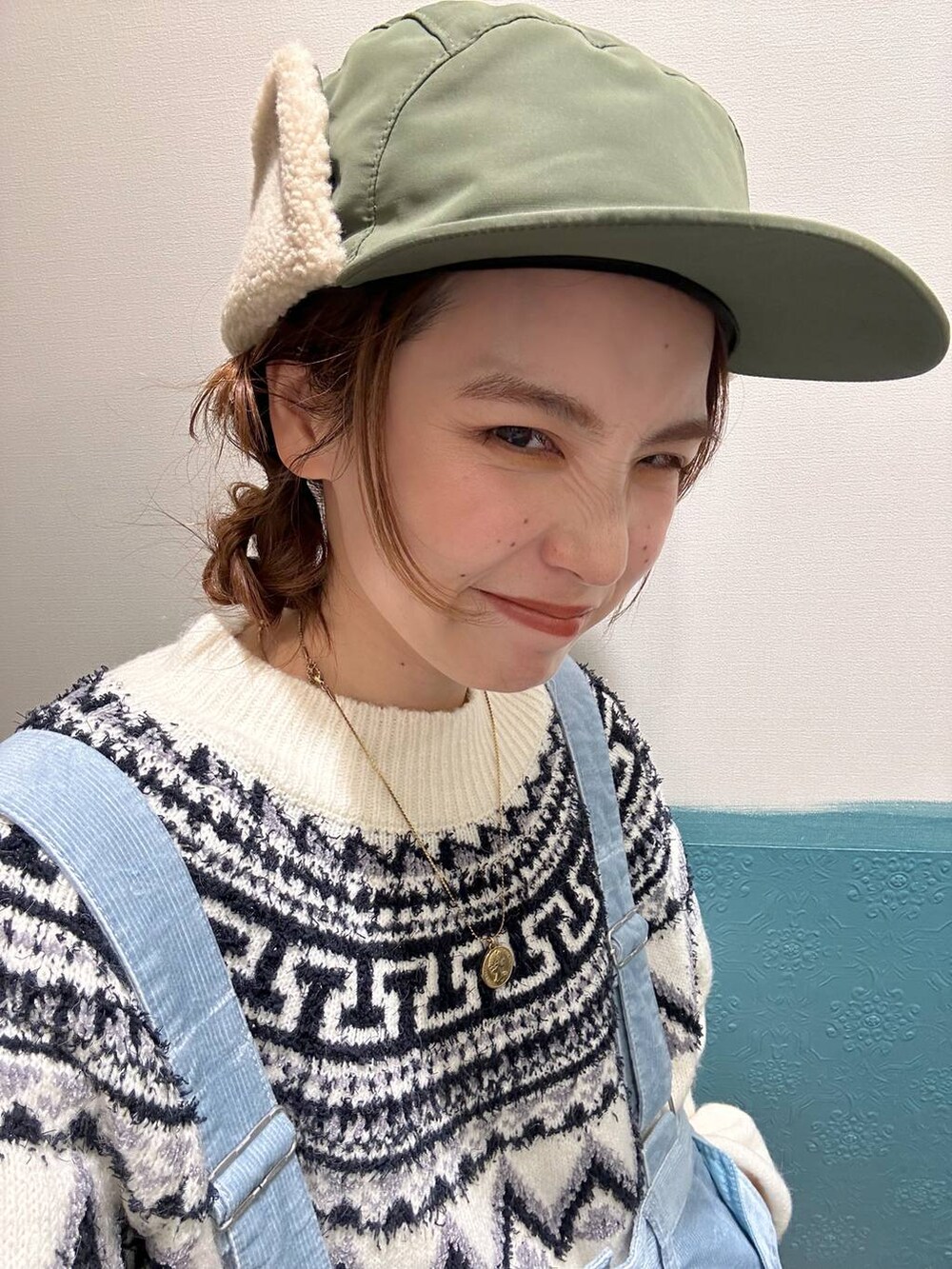 ブルー系のその他パンツ、ベージュ系のニット/セーター、グリーン系のキャップを着用したレディースの冬コーディネートの2枚目の写真