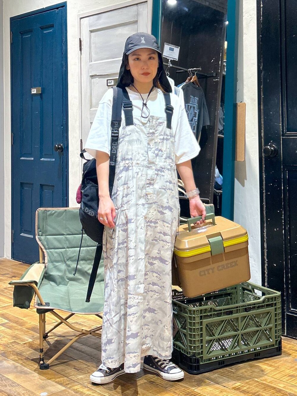 グリーン系のジャンパースカート、ブラック系のバックパック/リュック、ホワイト系のTシャツ/カットソーを着用したレディースの春コーディネートの2枚目の写真