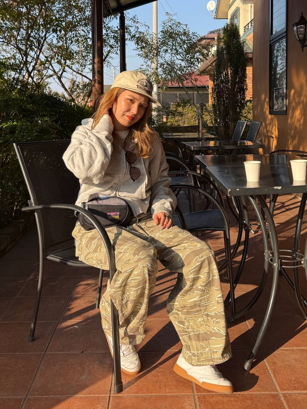 グレー系のボディバッグ/ウエストポーチ、ホワイト系のキャップを着用したレディースの冬コーディネートの2枚目の写真