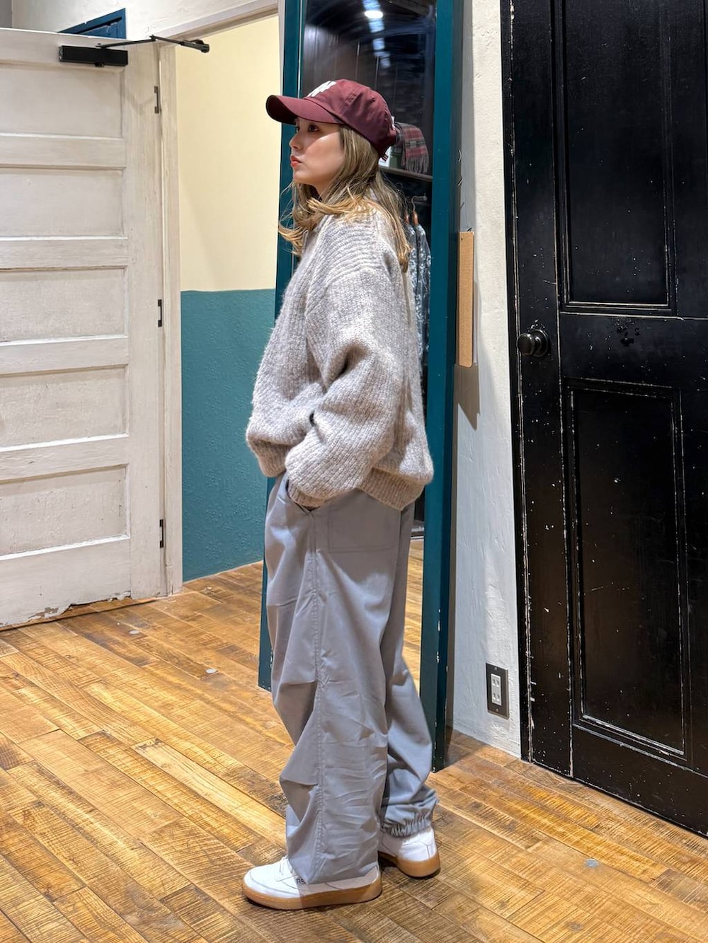 グレー系のその他パンツ、ベージュ系のカーディガン/ボレロ、レッド系のキャップを着用したレディースの冬コーディネートの3枚目の写真