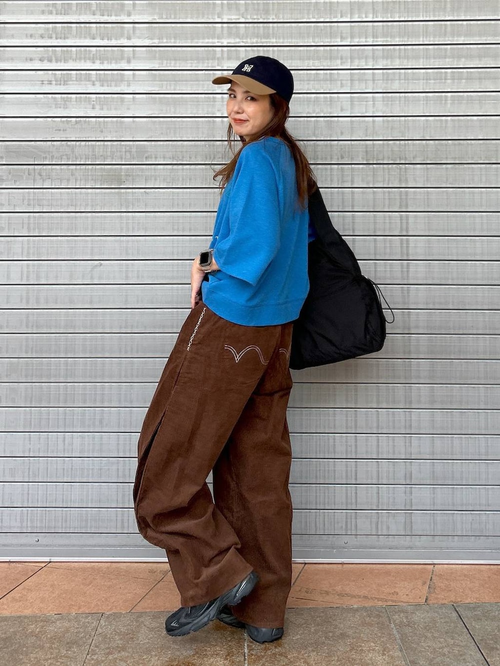 ブラック系のスニーカー、ブルー系のTシャツ/カットソー、ブラック系のトートバッグを着用したレディースの秋コーディネートの3枚目の写真