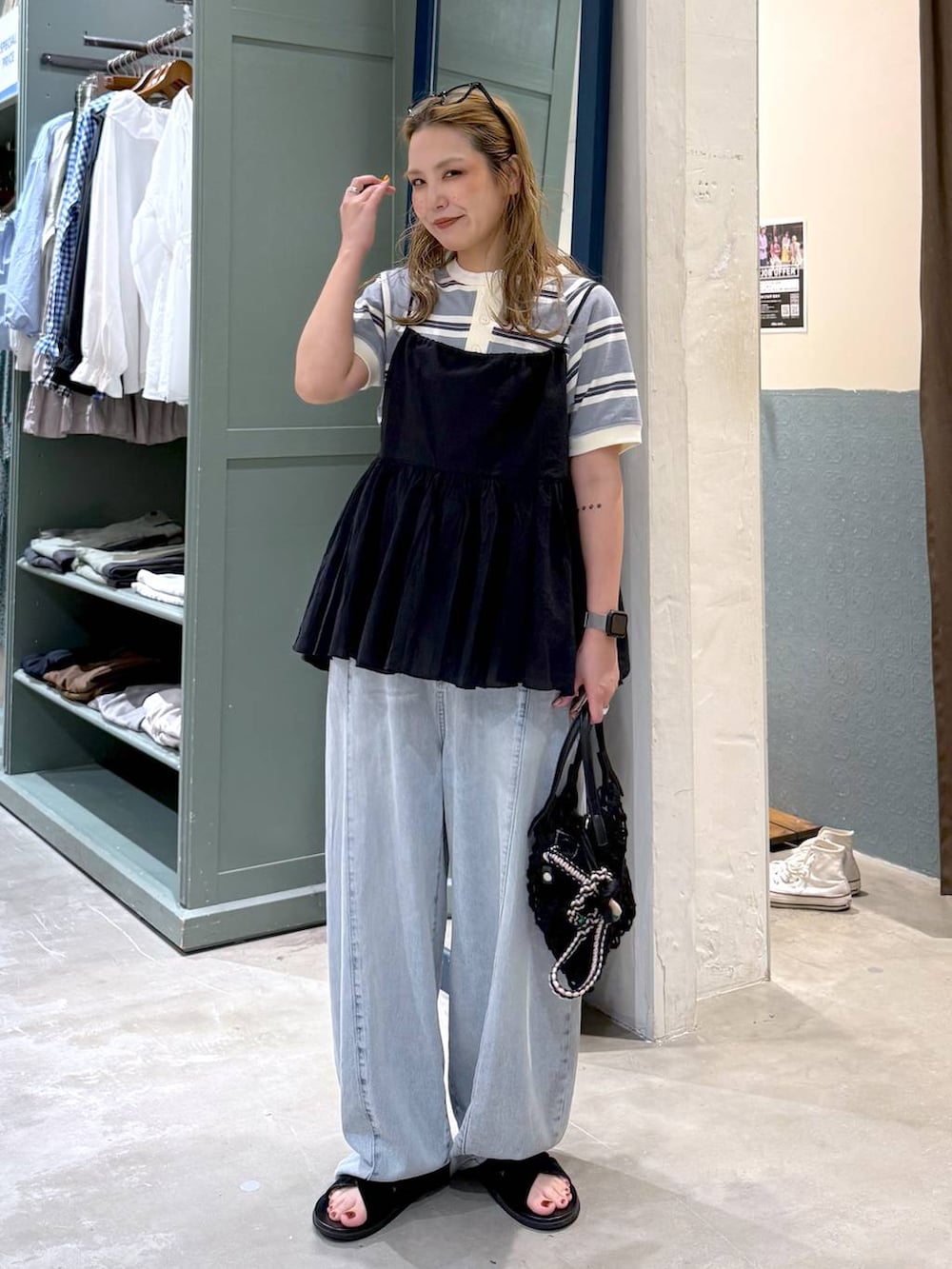 ブルー系のデニムパンツ、ブラック系のトートバッグ、ブラック系のキャミソールを着用したレディースの春コーディネートの2枚目の写真