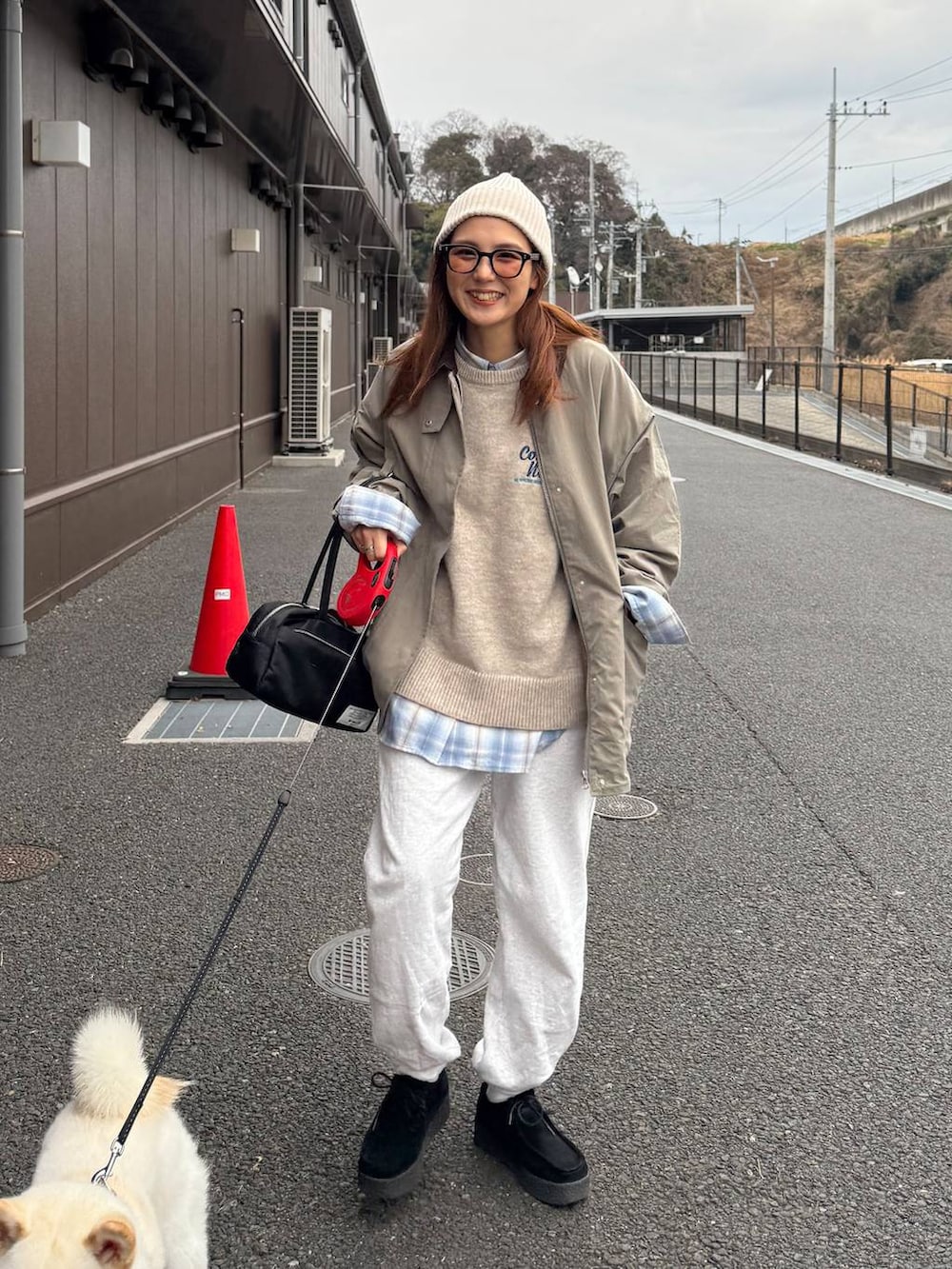 グレー系のスウェットパンツ、ベージュ系のニット/セーター、ブラック系のボストンバッグを着用したレディースの冬コーディネートの2枚目の写真