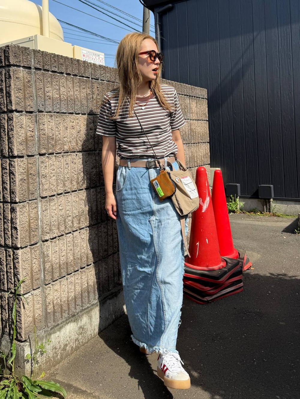 ベージュ系のショルダーバッグ、ブルー系のデニムスカート、ブラウン系のコインケースを着用したレディースの春コーディネートの3枚目の写真