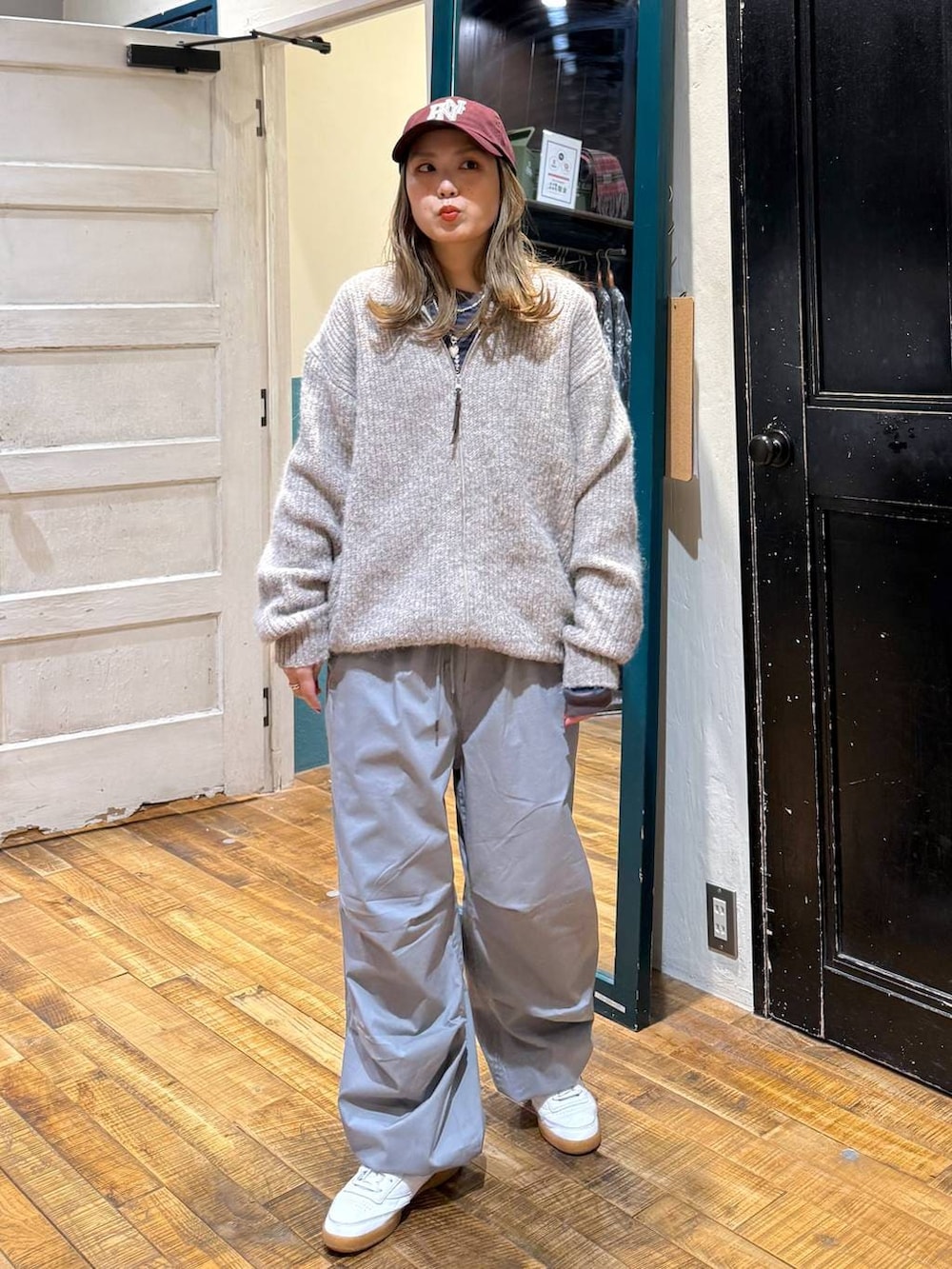 グレー系のその他パンツ、ベージュ系のカーディガン/ボレロ、レッド系のキャップを着用したレディースの冬コーディネートの5枚目の写真