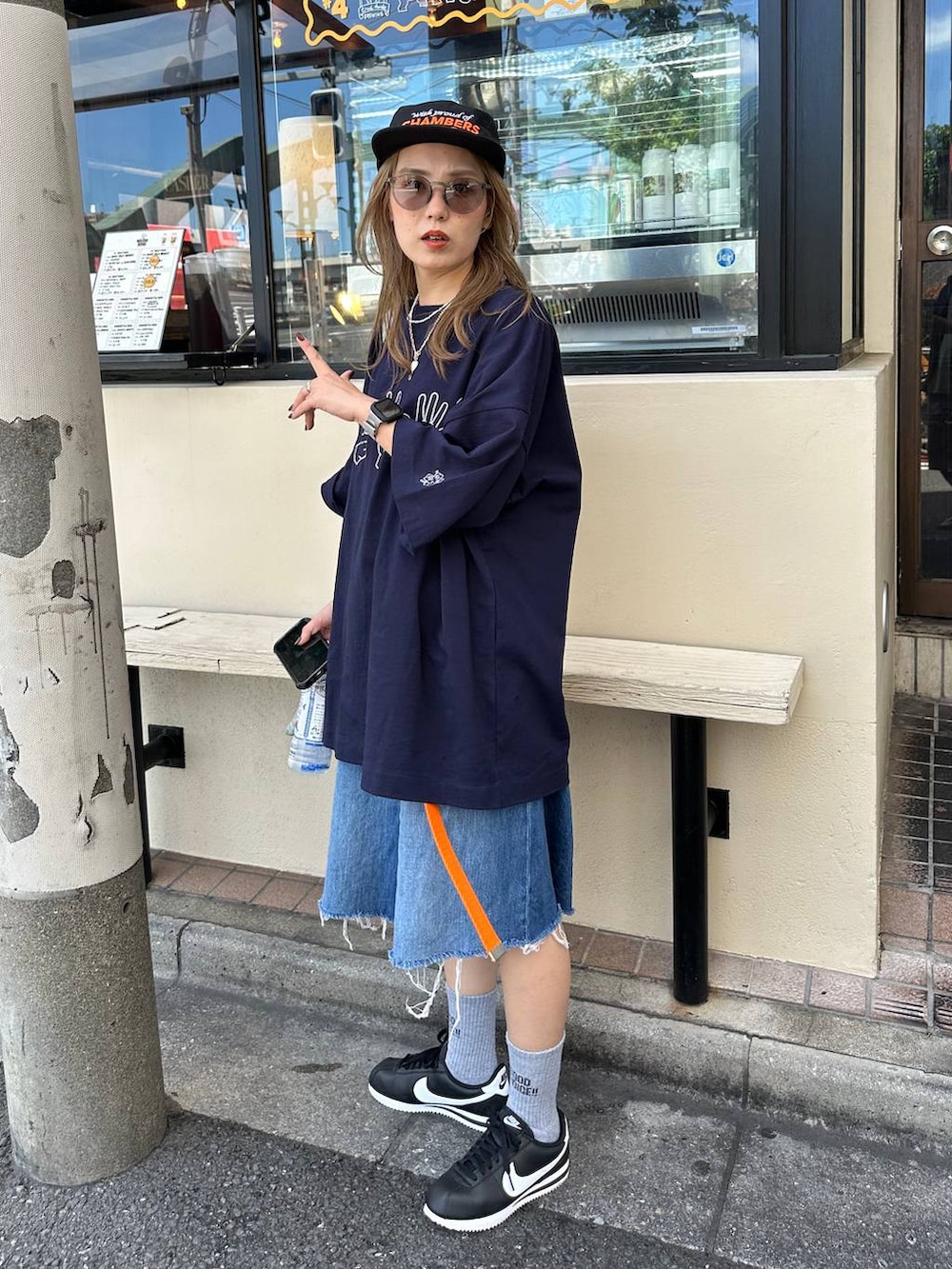ブルー系のデニムパンツ、オレンジ系のトートバッグ、オレンジ系のベルトを着用したレディースの夏コーディネートの3枚目の写真