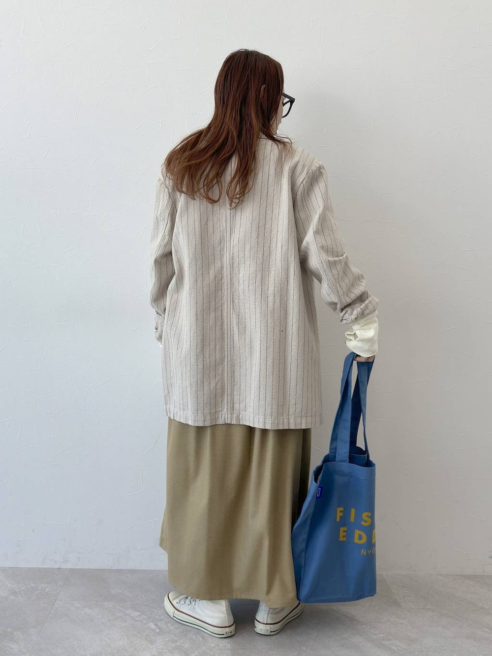 ベージュ系のテーラードジャケット、ブルー系のトートバッグ、ホワイト系のスウェットを着用したレディースの冬コーディネートの3枚目の写真