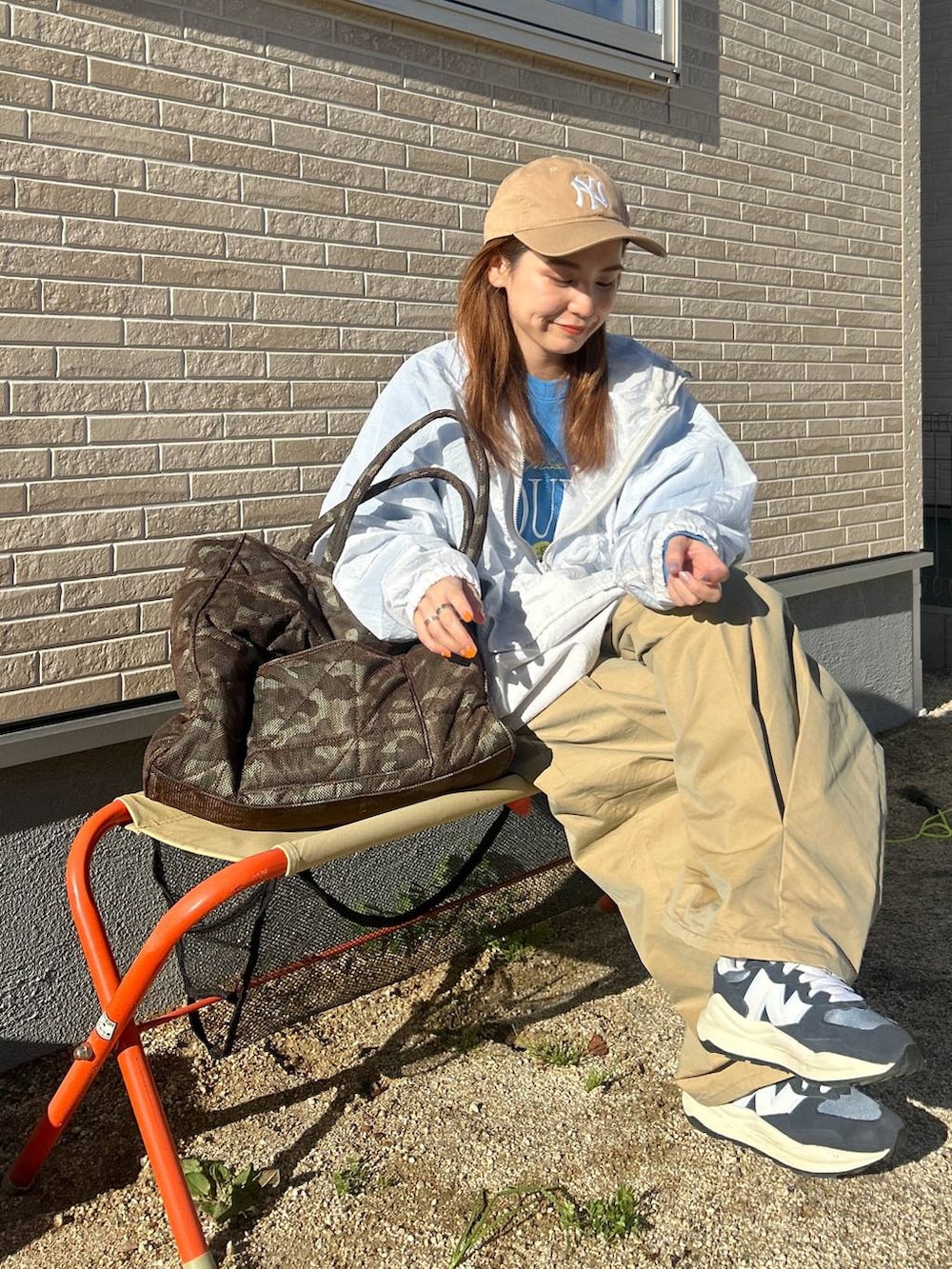 ベージュ系のチノパンツ、ホワイト系のマウンテンパーカー、ブルー系のスウェットを着用したレディースの春コーディネートの2枚目の写真