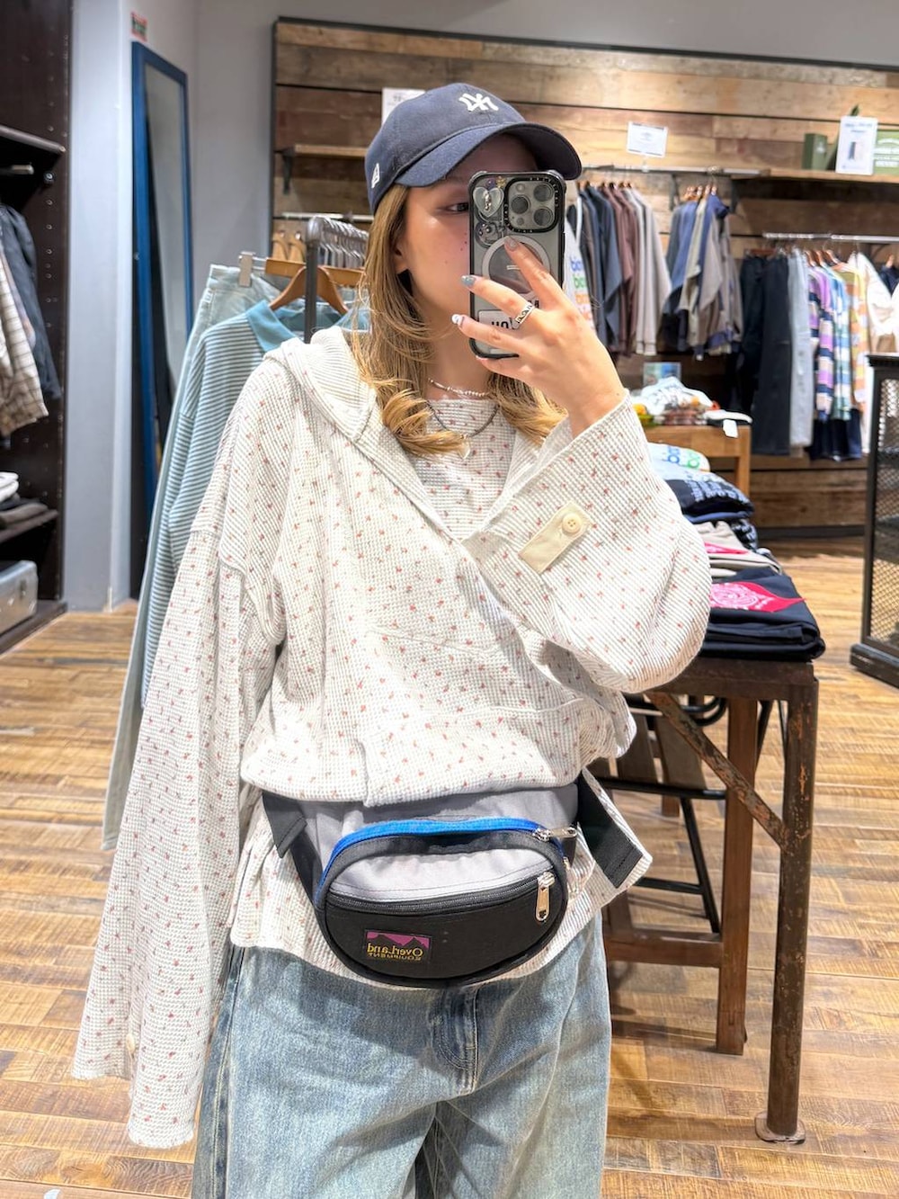 ブルー系のデニムパンツ、ベージュ系のパーカー、グレー系のボディバッグ/ウエストポーチを着用したレディースの冬コーディネートの3枚目の写真