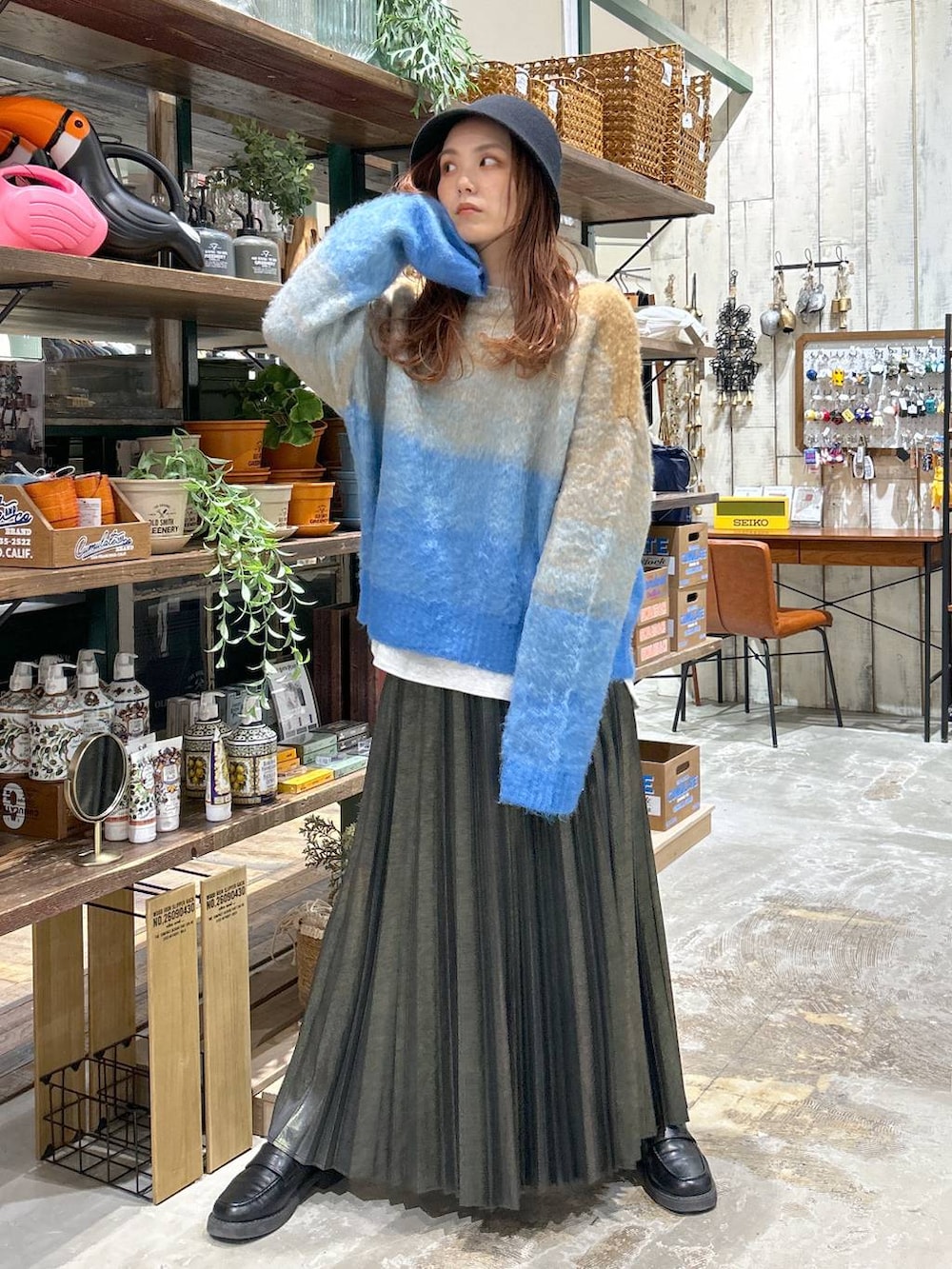 ブラック系のローファー、ブルー系のニット/セーター、ベージュ系のスカートを着用したレディースの冬コーディネートの2枚目の写真
