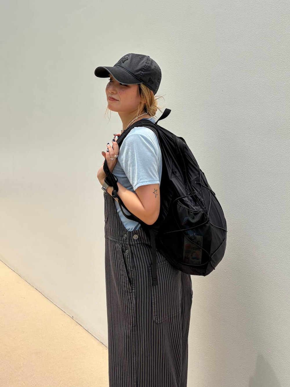 ブラック系のバックパック/リュック、ブルー系のTシャツ/カットソー、グレー系のサロペット/オーバーオールを着用したレディースの夏コーディネートの5枚目の写真