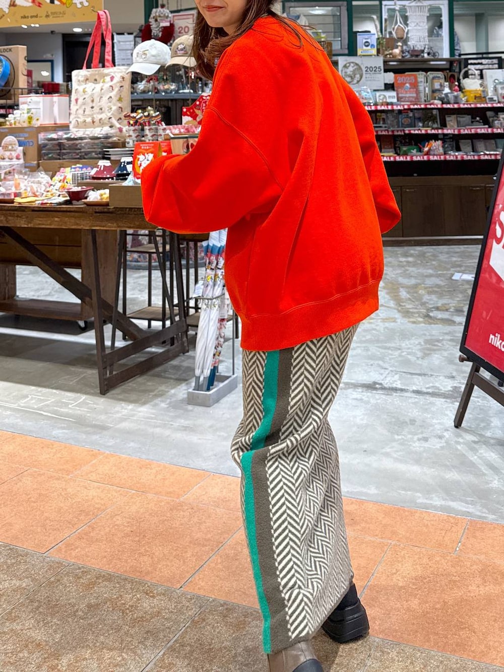 オレンジ系のスウェット、ブラウン系のブーツ、ブラウン系のスカートを着用したレディースの冬コーディネートの5枚目の写真