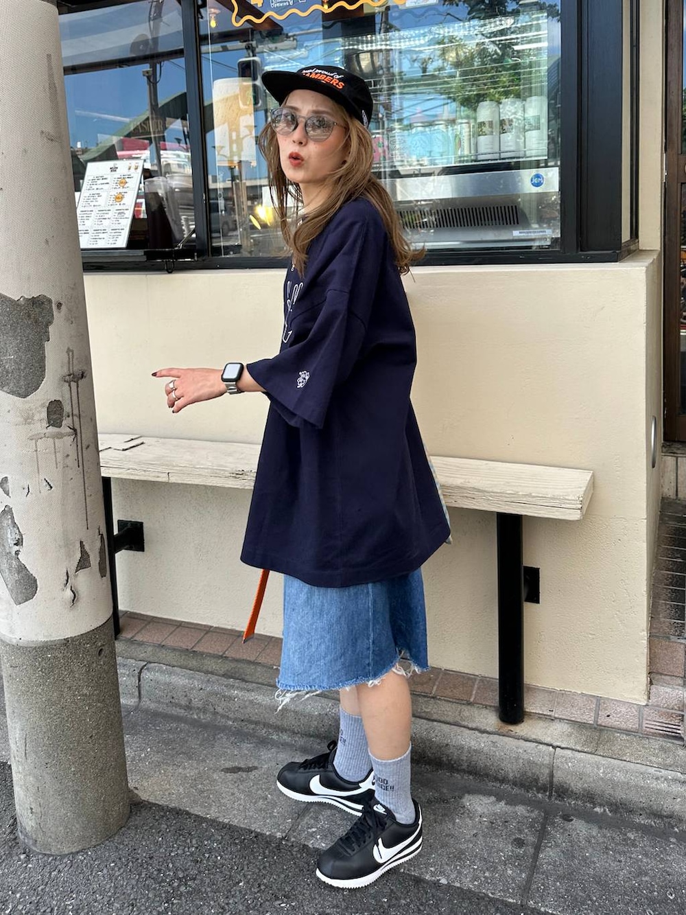 ブルー系のデニムパンツ、オレンジ系のトートバッグ、オレンジ系のベルトを着用したレディースの夏コーディネートの2枚目の写真