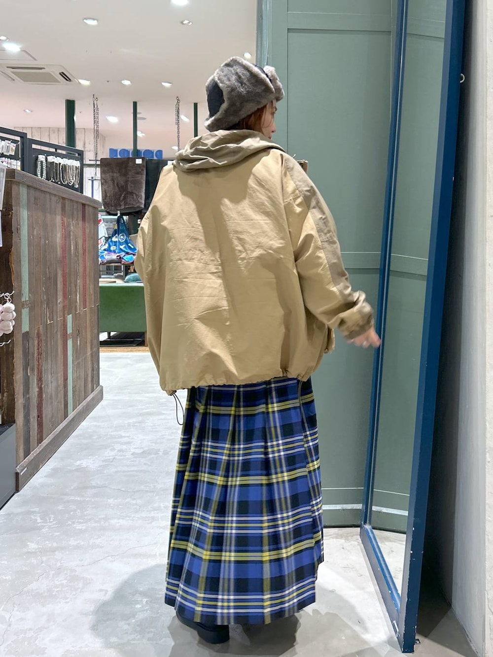 ブルー系のスカート、ベージュ系のマウンテンパーカー、ブラック系のニット/セーターを着用したレディースの冬コーディネートの3枚目の写真