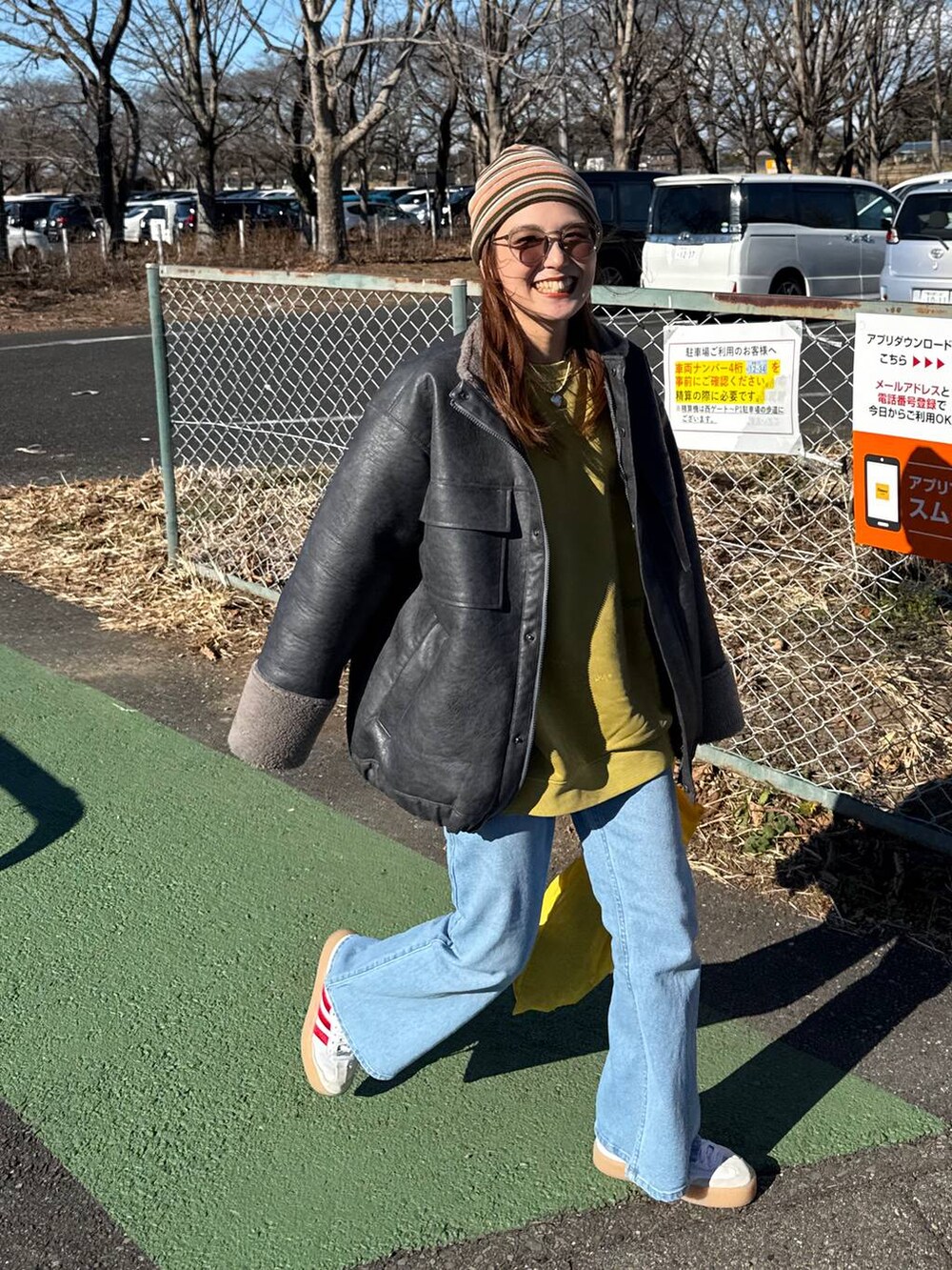 グレー系のブルゾン、ブルー系のデニムパンツ、イエロー系のスウェットを着用したレディースの冬コーディネートの2枚目の写真