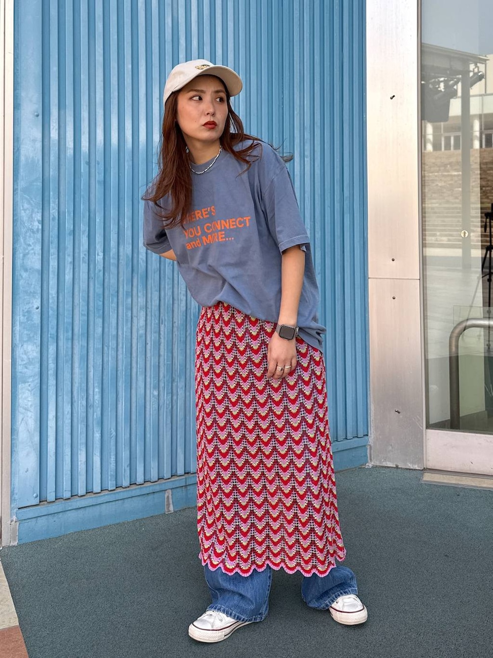 ブルー系のデニムパンツ、ピンク系のスカート、ベージュ系のキャップを着用したレディースの春コーディネートの2枚目の写真