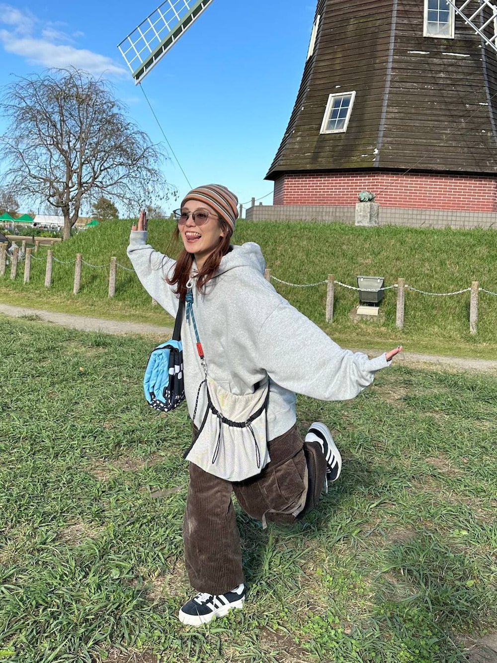 ブラウン系のカーゴパンツ、グレー系のパーカー、グレー系のショルダーバッグを着用したレディースの秋コーディネートの2枚目の写真