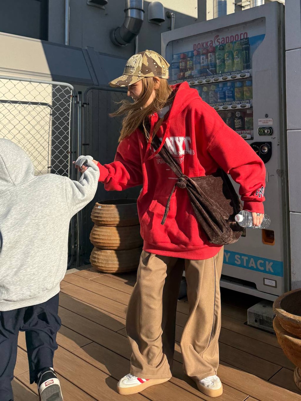 レッド系のパーカー、ベージュ系のキャップを着用したレディースの秋コーディネートの2枚目の写真