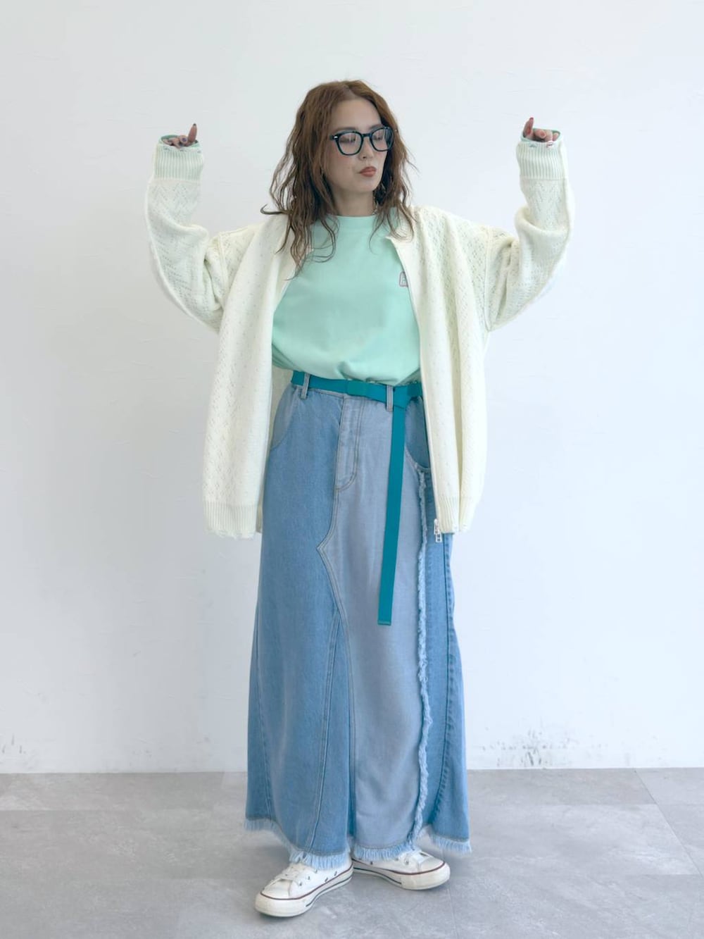 ブルー系のデニムスカート、ホワイト系のブルゾン、グリーン系のTシャツ/カットソーを着用したレディースの冬コーディネートの2枚目の写真