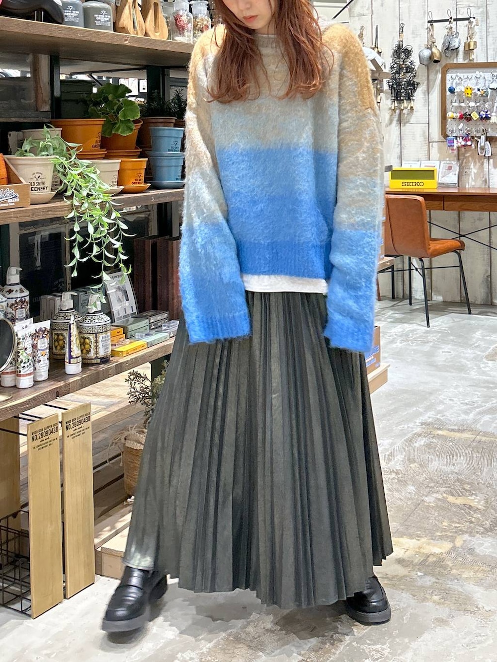 ブラック系のローファー、ブルー系のニット/セーター、ベージュ系のスカートを着用したレディースの冬コーディネートの3枚目の写真