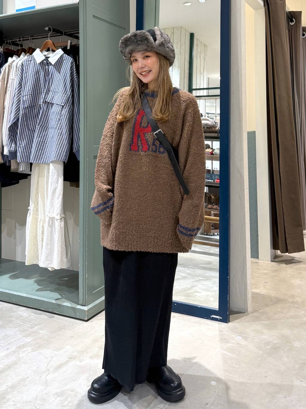 ブラック系のショルダーバッグ、ブラック系のスカート、ブラック系のブーツを着用したレディースの秋コーディネートの3枚目の写真