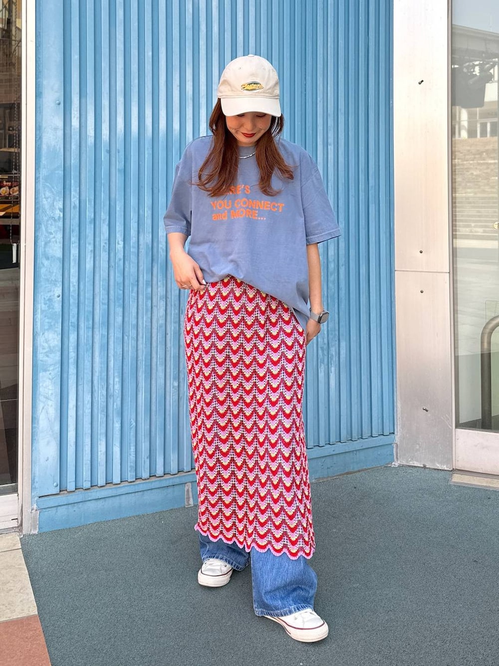 ブルー系のデニムパンツ、ピンク系のスカート、ベージュ系のキャップを着用したレディースの春コーディネートの3枚目の写真